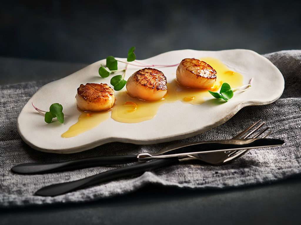 Pan fried Scallops with orange sauce on plate. Food photography by Food Photographer London, Michael Michaels