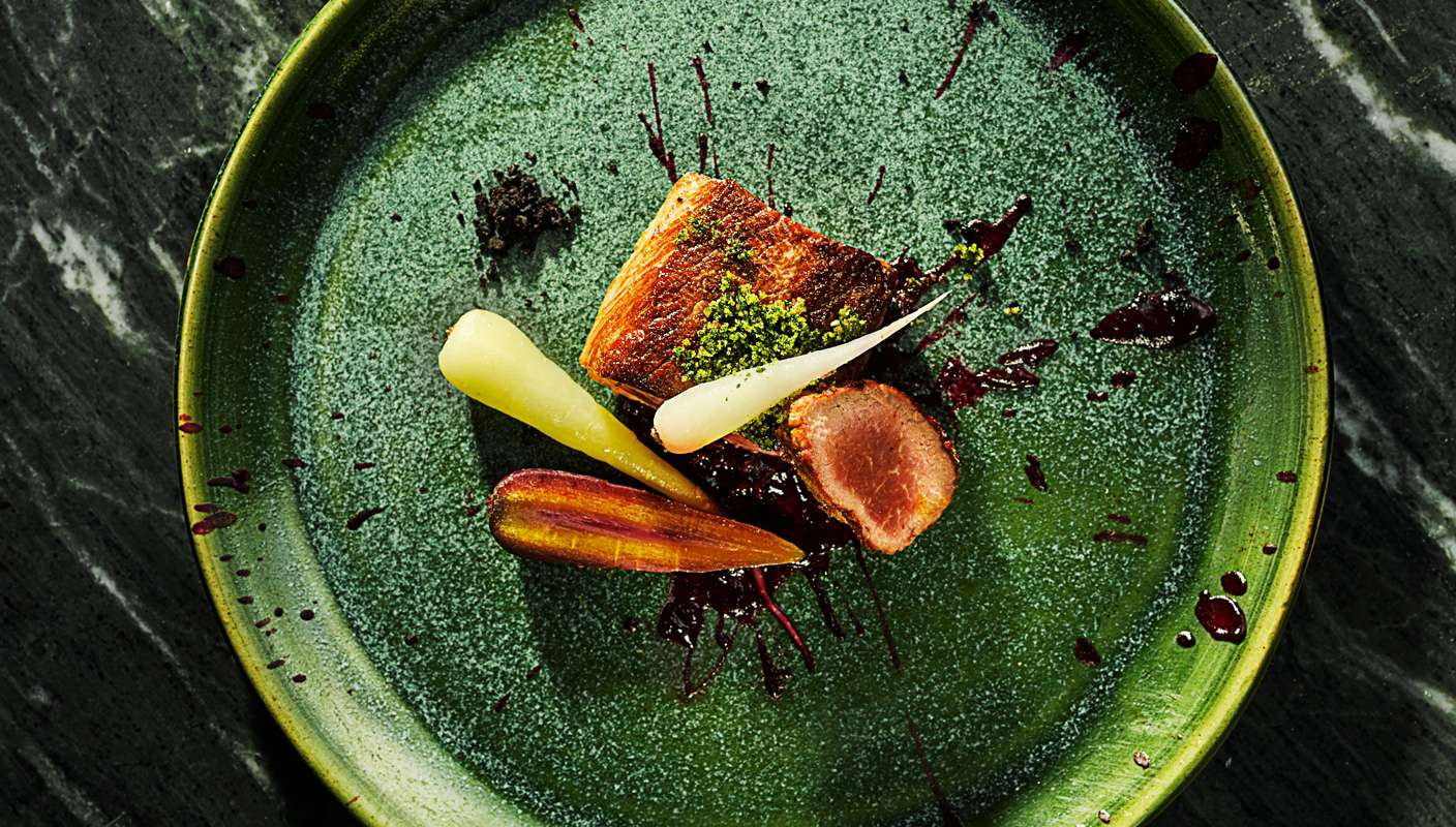 chef presented Roasted lamb with carrots on vibrant green textured plate by London food photographer Michael Michaels